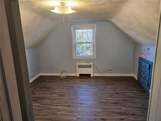 bonus room with dark hardwood / wood-style flooring, a textured ceiling, radiator, and vaulted ceiling