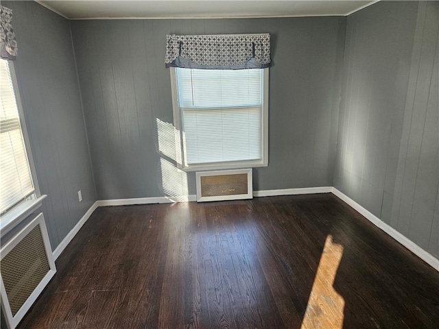 spare room featuring crown molding, dark wood-type flooring, and radiator