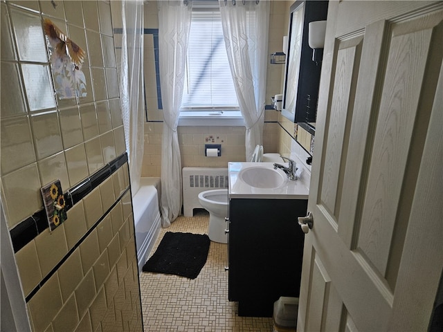 full bathroom with radiator, tile walls, toilet, vanity, and shower / tub combo