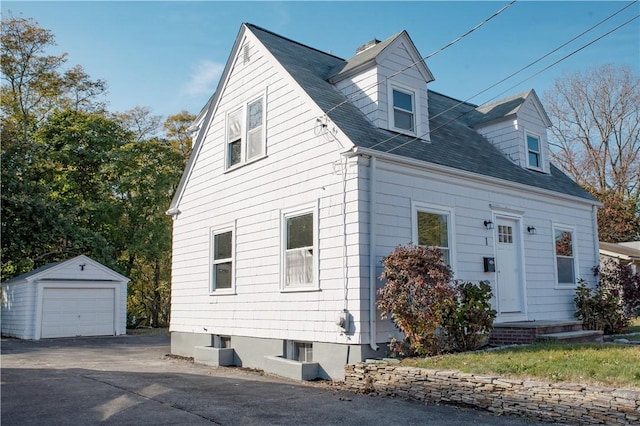 cape cod-style house featuring a garage and an outbuilding