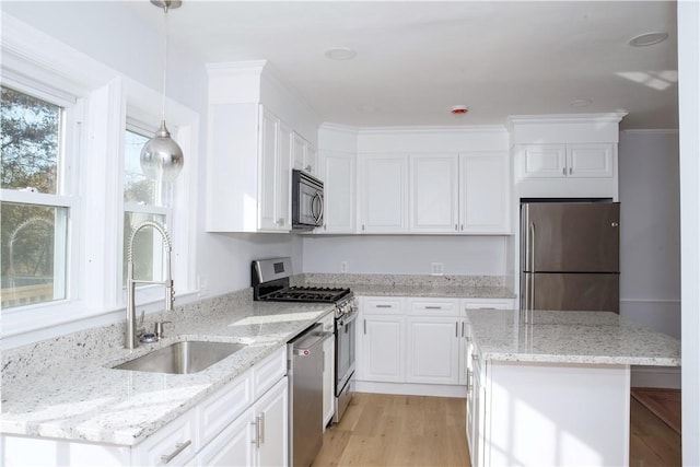 kitchen featuring light stone counters, sink, pendant lighting, and appliances with stainless steel finishes