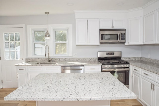 kitchen featuring sink, stainless steel appliances, pendant lighting, light hardwood / wood-style floors, and white cabinets