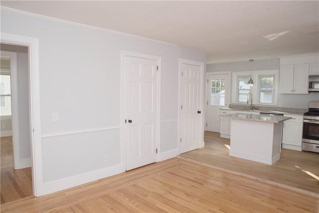 kitchen with white cabinets, a kitchen island, light wood-type flooring, and appliances with stainless steel finishes