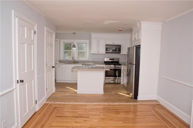 kitchen with sink, stainless steel appliances, a kitchen island, light hardwood / wood-style flooring, and white cabinets