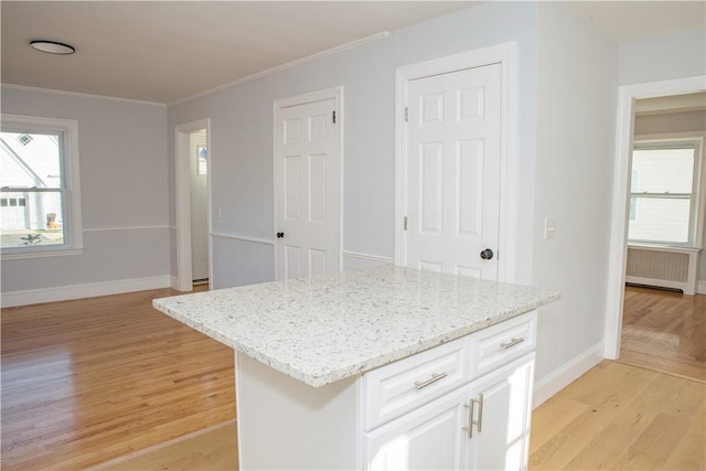 kitchen featuring radiator, a center island, light stone counters, light hardwood / wood-style floors, and white cabinets