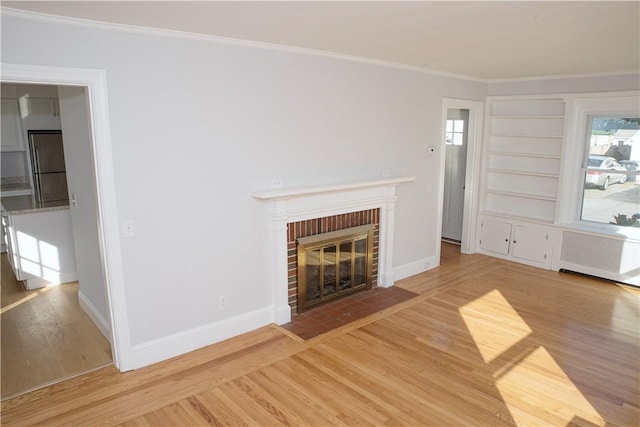 unfurnished living room featuring hardwood / wood-style flooring, a healthy amount of sunlight, ornamental molding, and a fireplace