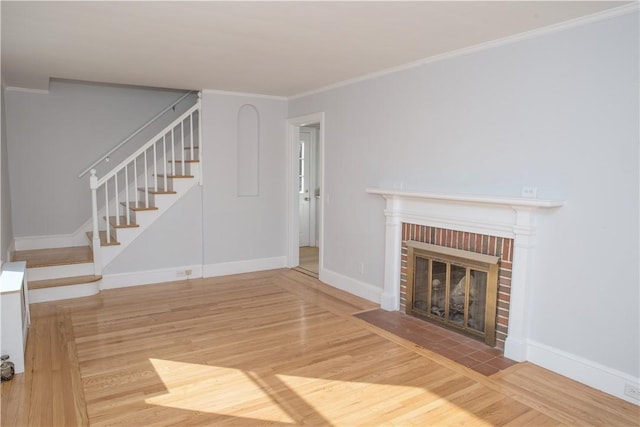 unfurnished living room featuring wood-type flooring, a brick fireplace, and ornamental molding