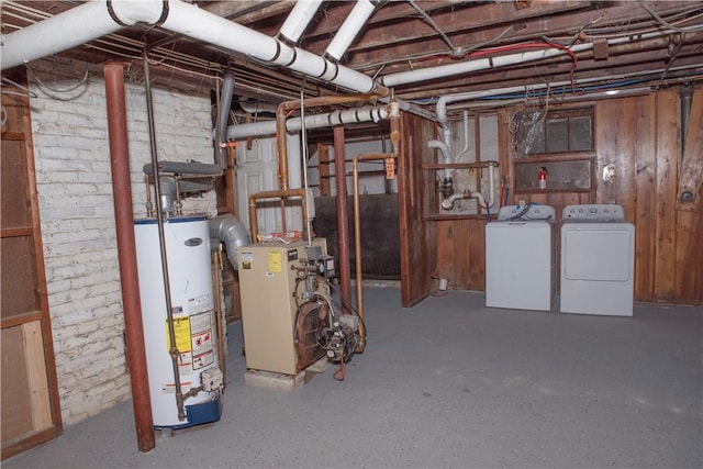 basement with gas water heater, brick wall, and washing machine and clothes dryer