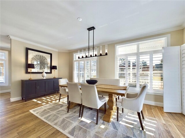 dining space with light hardwood / wood-style flooring, a wealth of natural light, and crown molding