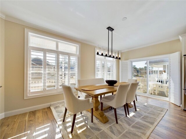 dining area featuring light hardwood / wood-style flooring, crown molding, and a notable chandelier