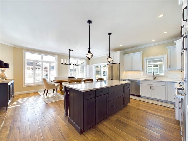 kitchen with white cabinets, appliances with stainless steel finishes, light hardwood / wood-style flooring, and a kitchen island