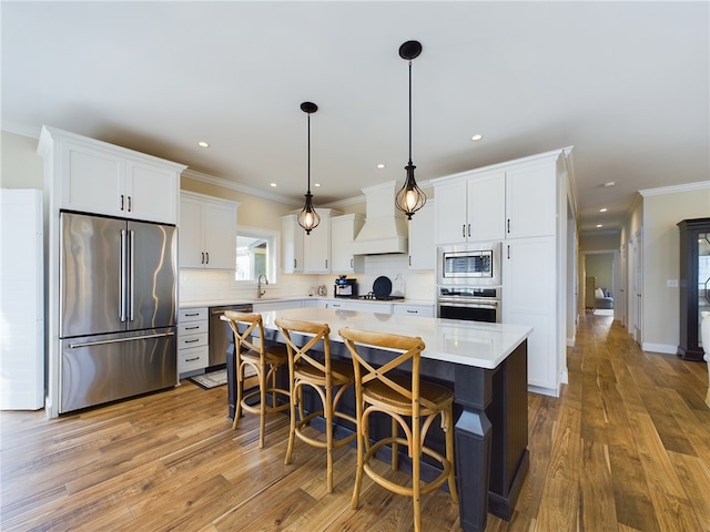 kitchen with premium range hood, hardwood / wood-style flooring, a kitchen island, white cabinetry, and stainless steel appliances