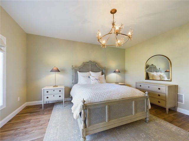 bedroom with wood-type flooring and an inviting chandelier