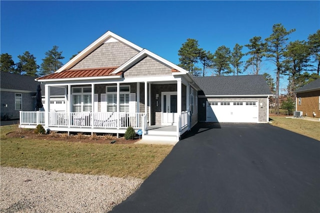 view of front of property featuring a porch, a garage, cooling unit, and a front lawn