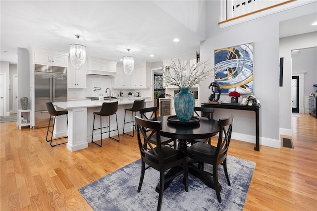 dining room with light hardwood / wood-style floors and a notable chandelier