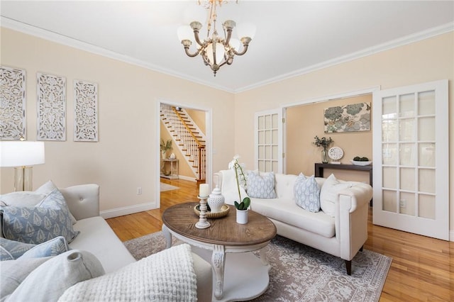 living room featuring ornamental molding, a notable chandelier, and light wood-type flooring