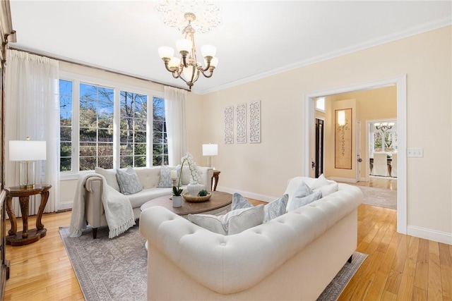 living room featuring crown molding, light hardwood / wood-style flooring, and a chandelier