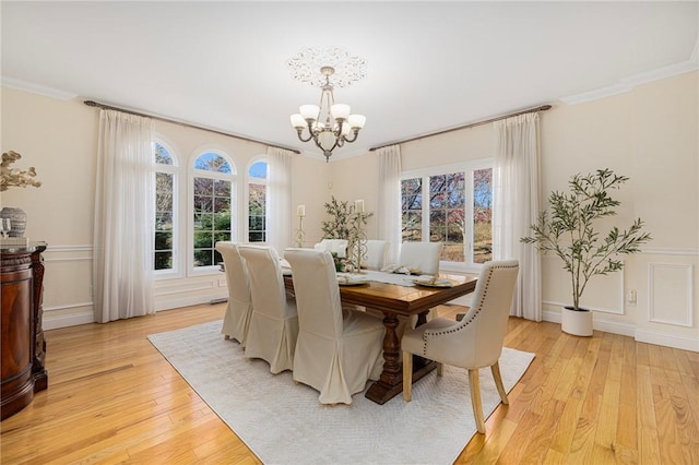 dining room with light hardwood / wood-style floors, a notable chandelier, and ornamental molding