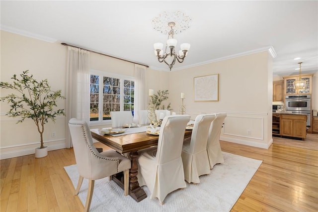 dining area with an inviting chandelier, light hardwood / wood-style flooring, and crown molding