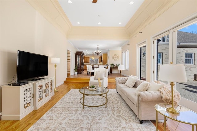 living room featuring ceiling fan with notable chandelier, light wood-type flooring, ornamental molding, and a wealth of natural light