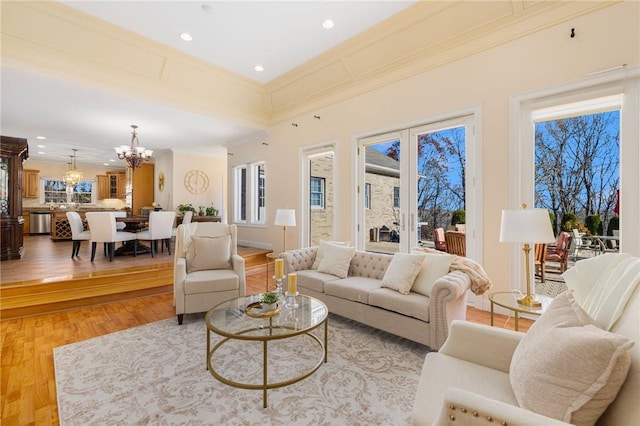 living room with light hardwood / wood-style floors, ornamental molding, and an inviting chandelier