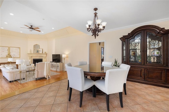 dining space with light tile patterned floors, ceiling fan with notable chandelier, and ornamental molding