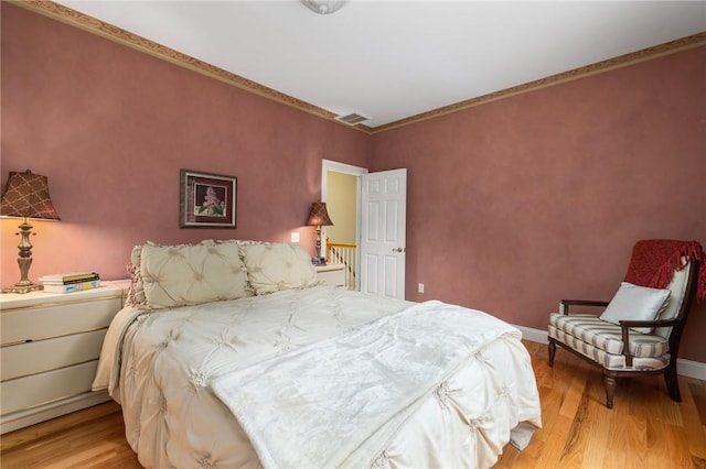 bedroom with light hardwood / wood-style floors and ornamental molding