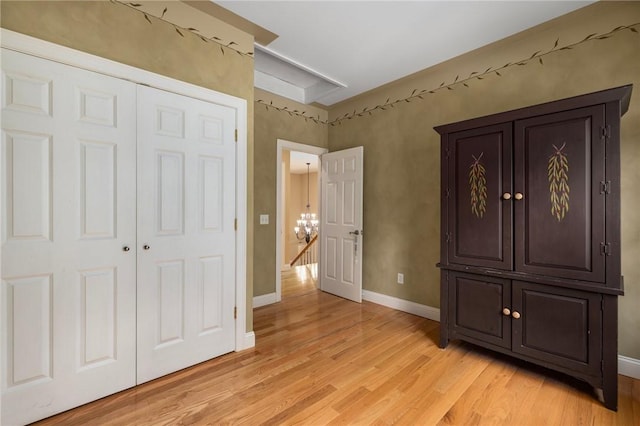 unfurnished bedroom featuring a chandelier, light wood-type flooring, and a closet