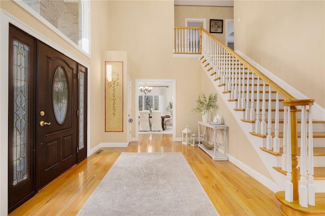 entrance foyer with a notable chandelier, wood-type flooring, and a high ceiling