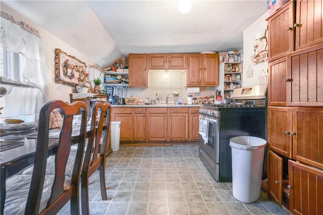 kitchen with decorative backsplash, a textured ceiling, vaulted ceiling, sink, and stainless steel range with gas cooktop