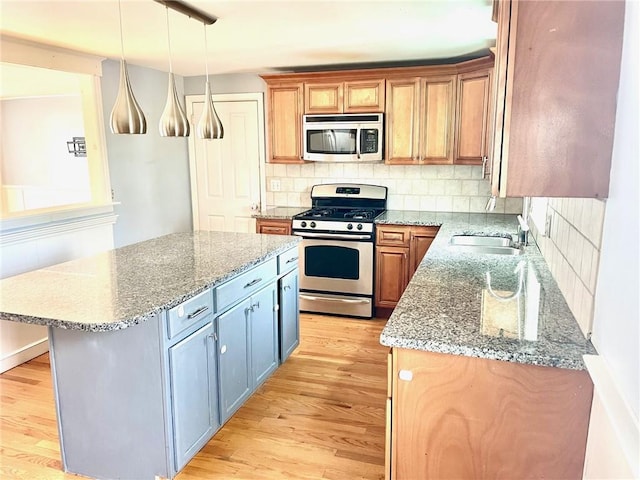 kitchen with pendant lighting, a center island, sink, stone countertops, and stainless steel appliances