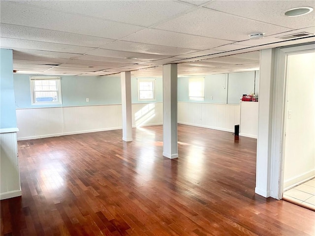 basement with a paneled ceiling and dark wood-type flooring