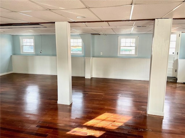 basement featuring dark hardwood / wood-style flooring, a drop ceiling, and a healthy amount of sunlight