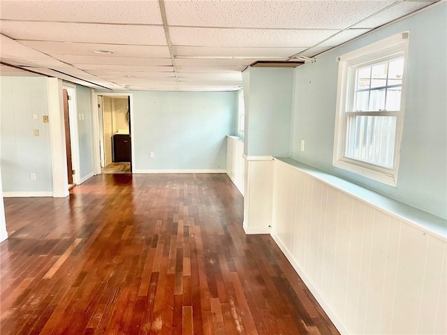 unfurnished room featuring a paneled ceiling, dark hardwood / wood-style floors, and wooden walls