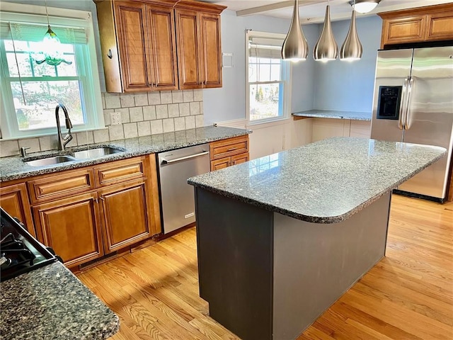 kitchen featuring sink, a center island, light hardwood / wood-style flooring, decorative backsplash, and appliances with stainless steel finishes