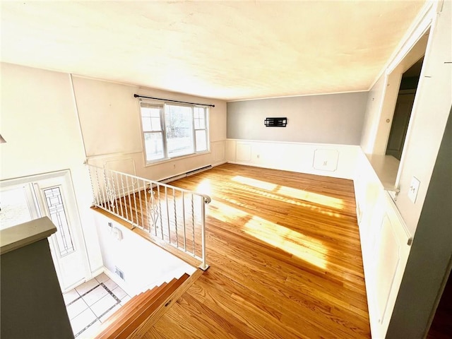 unfurnished living room featuring a baseboard radiator and light hardwood / wood-style floors