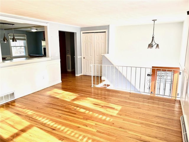 unfurnished room featuring baseboard heating and wood-type flooring