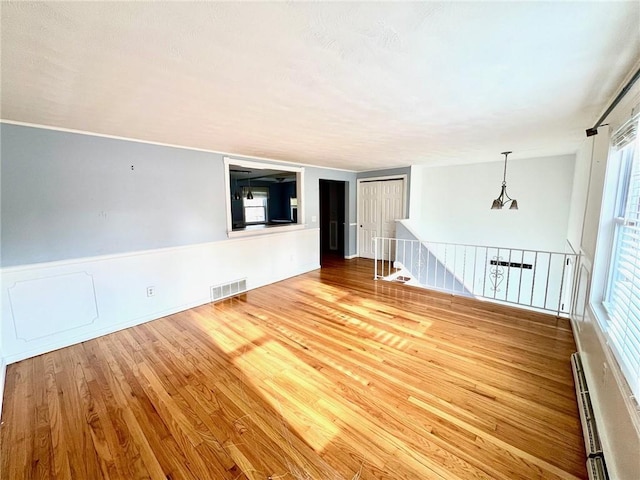 unfurnished room with wood-type flooring and a baseboard heating unit