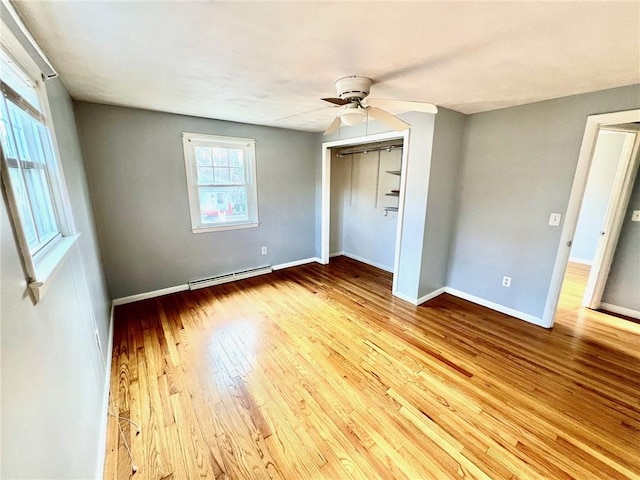 unfurnished bedroom featuring baseboard heating, ceiling fan, a closet, and light wood-type flooring