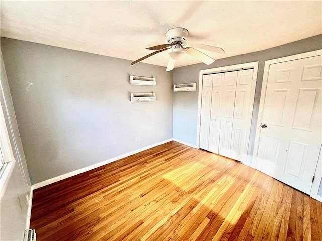 unfurnished bedroom with a wall mounted AC, ceiling fan, and hardwood / wood-style floors