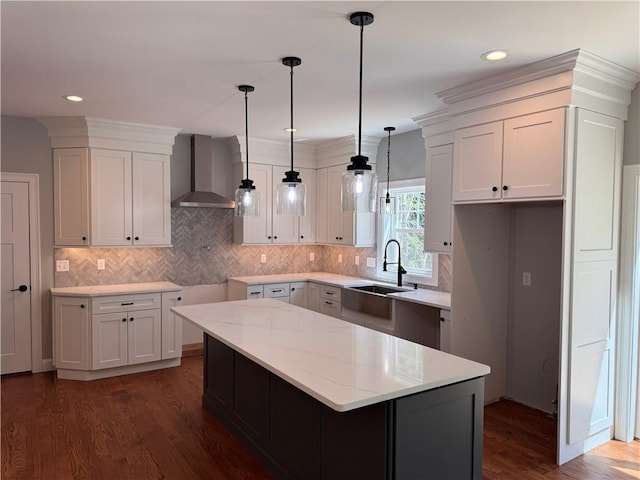 kitchen featuring wall chimney exhaust hood, dark hardwood / wood-style floors, white cabinetry, and sink