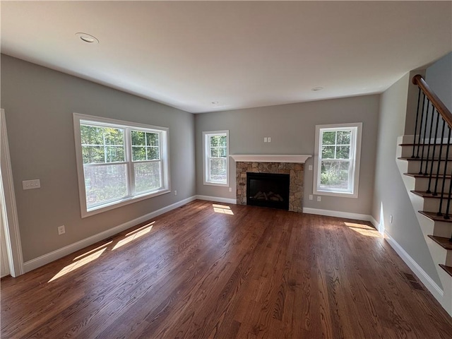 unfurnished living room featuring a healthy amount of sunlight and dark hardwood / wood-style flooring