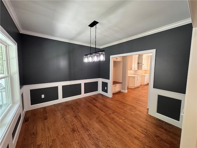 unfurnished dining area with hardwood / wood-style floors and ornamental molding