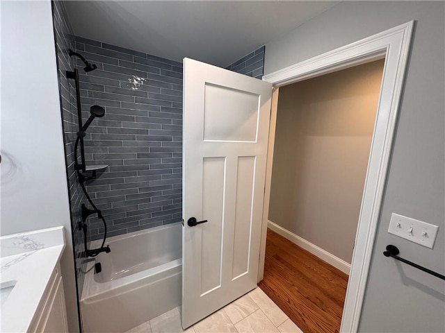 bathroom with hardwood / wood-style flooring, tiled shower / bath combo, and vanity