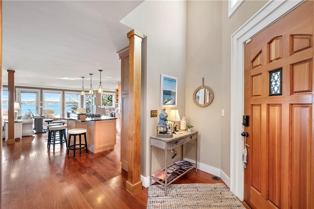 foyer featuring dark hardwood / wood-style flooring, decorative columns, and a water view