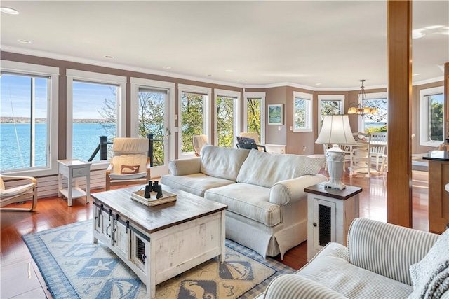 living room featuring ornamental molding, a water view, a healthy amount of sunlight, and a notable chandelier