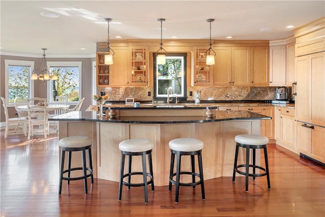 kitchen featuring a breakfast bar area, light brown cabinets, an island with sink, and a healthy amount of sunlight