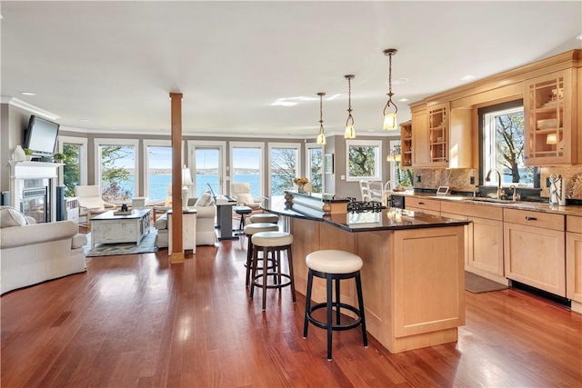 kitchen with a kitchen island, a kitchen breakfast bar, dark hardwood / wood-style flooring, pendant lighting, and a water view