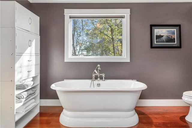 bathroom featuring toilet, wood-type flooring, and a bath