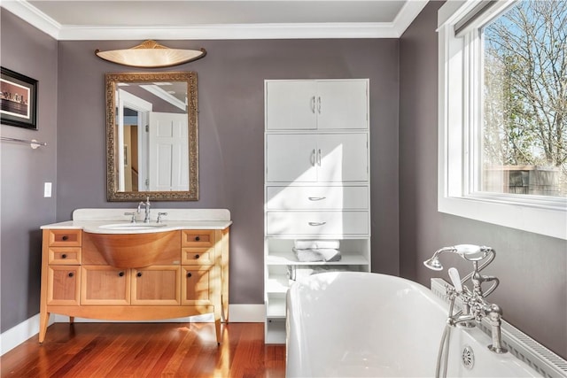 bathroom with wood-type flooring, vanity, a tub to relax in, and crown molding